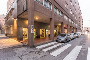 Un immeuble à plusieurs étages, avec un espace commercial au rez-de-chaussée et un passage piéton.