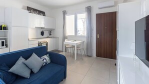 Um espaço compacto com cozinha compacta, área de refeições, sofá e televisão.