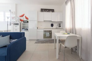 A compact living space with a kitchenette, a dining area, and a sofa. - Elianto (Bologna)