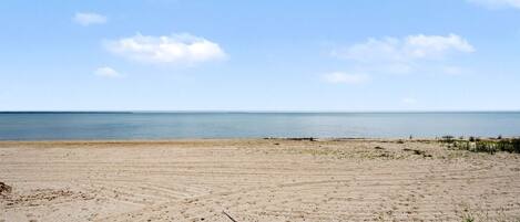 Une plage de sable fin, avec un ciel dégagé et une mer calme.