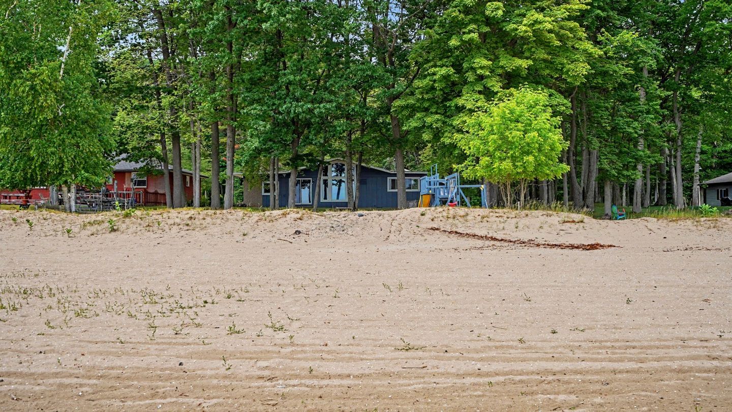 A sandy beach with a row of cabins and a playground.