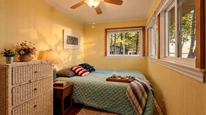 A bedroom with a bed, a dresser, a window, and a ceiling fan.