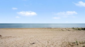 Una playa arenosa con cielo despejado y mar en calma.
