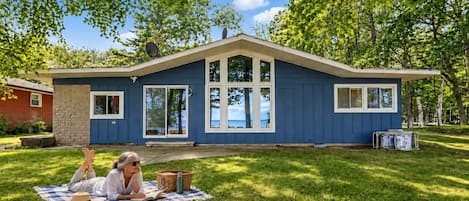 A house with a blue exterior, large windows, and a covered porch area.