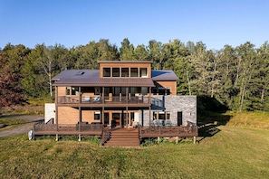 Ein modernes, zweistöckiges Haus mit Terrasse, großen Fenstern und einer Steinaußenwand.