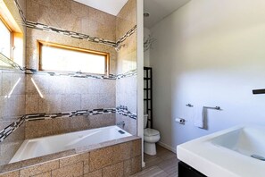 Ein Badezimmer mit Badewanne, Toilette und einem Fenster.