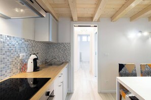 A modern kitchen with a black countertop, a coffee machine, and a tiled backsplash. - Andreini (Bologna)