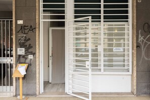 A building entrance with a metal gate, a door, and a wall with graffiti. - Andreini (Bologna)