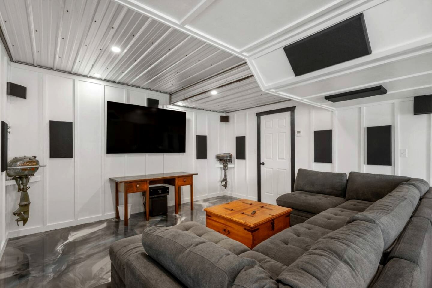 Una sala de estar moderna con un amplio sofá modular, una mesa de centro de madera, un televisor de pantalla plana montado en la pared y una chimenea.
