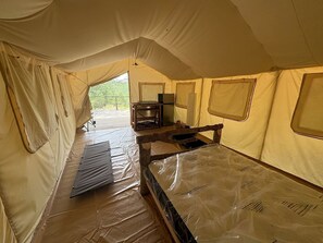 Ein Zelt mit Bett, Tisch und Stuhl.