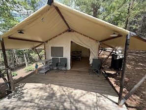 A tented structure with a covered seating area, a table, and chairs.