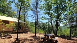 Ein bewaldeter Campingplatz mit Picknicktisch und Zelt.