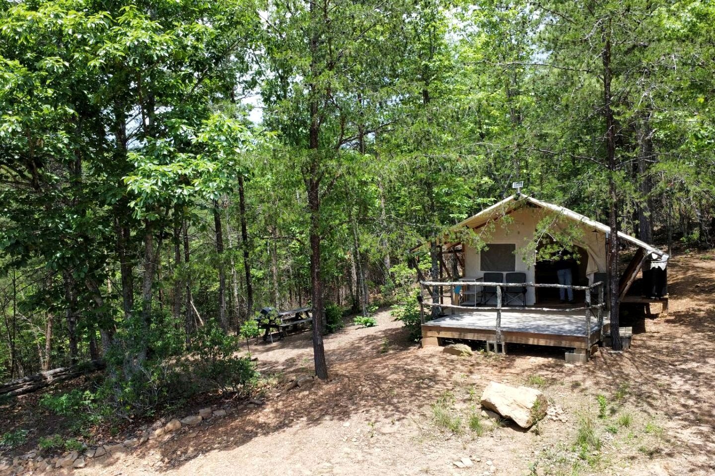 Una cabaña rústica con un porche, rodeada de un bosque denso.