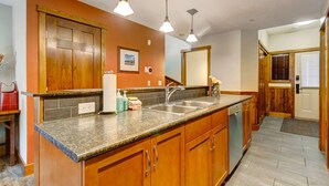 A kitchen with wooden cabinets, a granite countertop, a sink, and pendant lighting. - Warm Mountain View Retreat (Canmore)