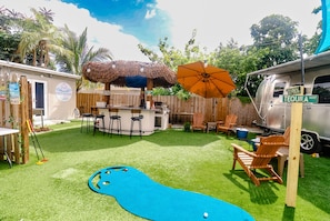 Ein Garten mit Poolbillard, Bar und Gartenmöbeln.