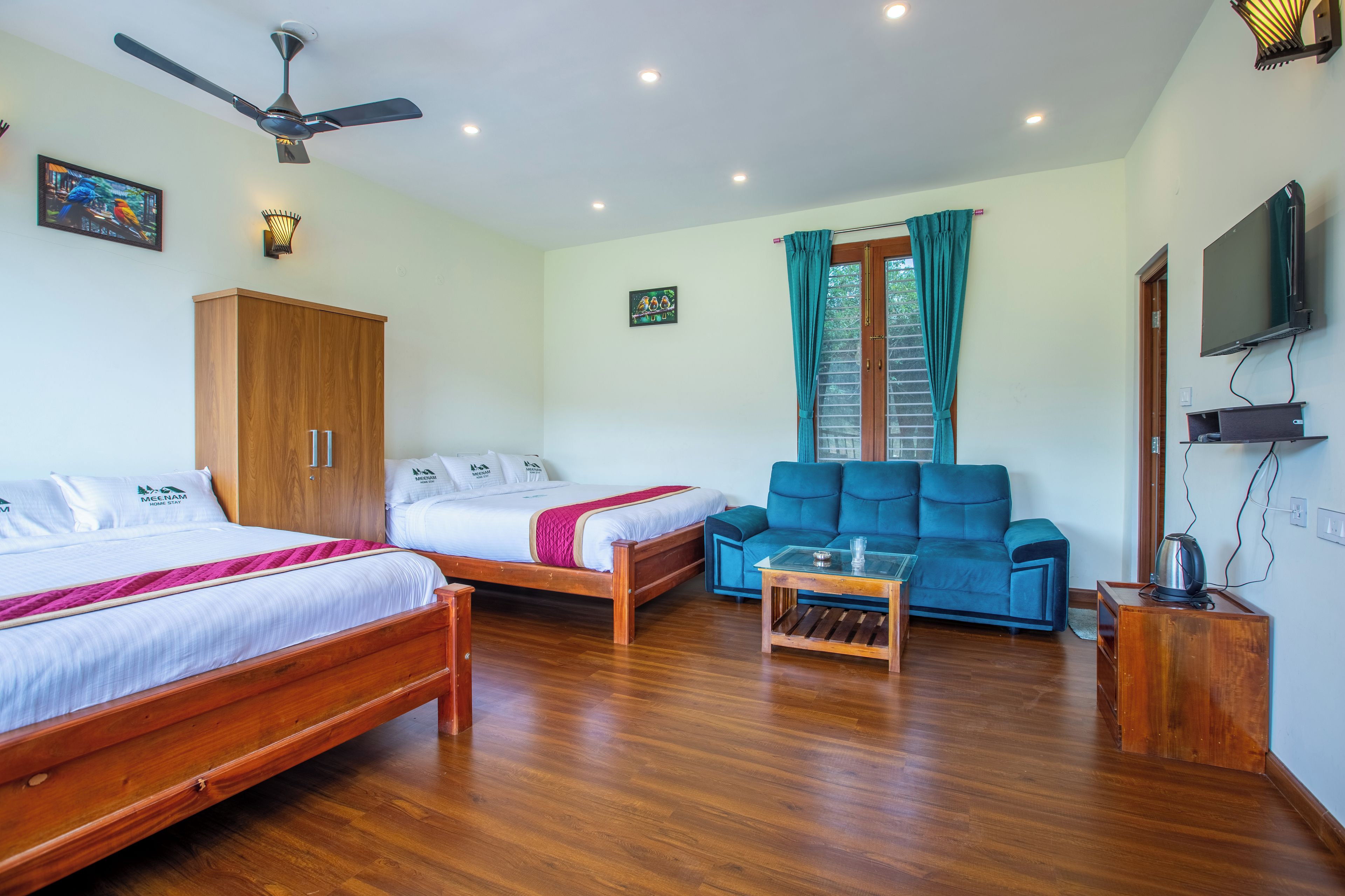 Una habitación de hotel con dos camas, un sofá, una mesa de centro, un ventilador de techo y un televisor.