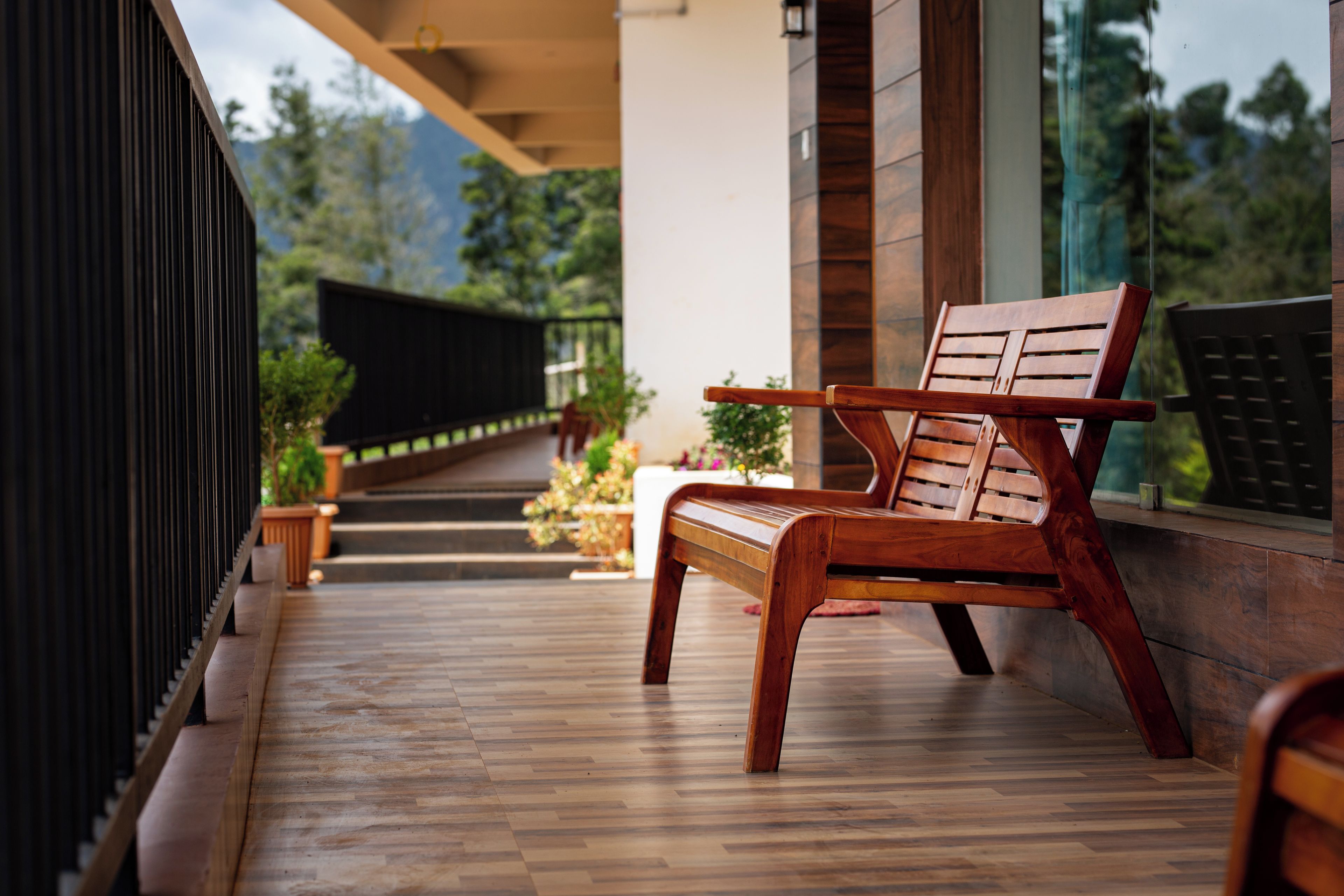 A wooden bench on a wooden deck with a view of a building and greenery.