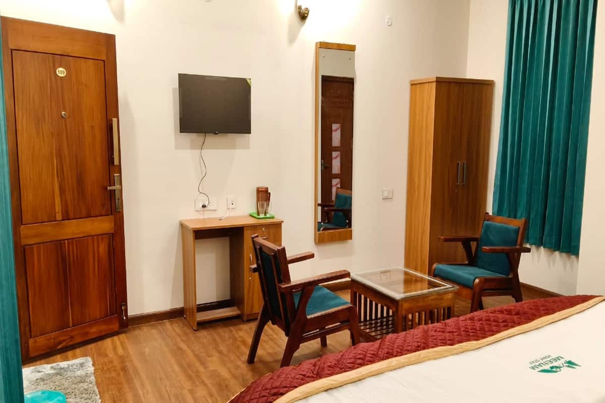 A hotel room with a bed, a desk, a chair, a television, and a wardrobe.