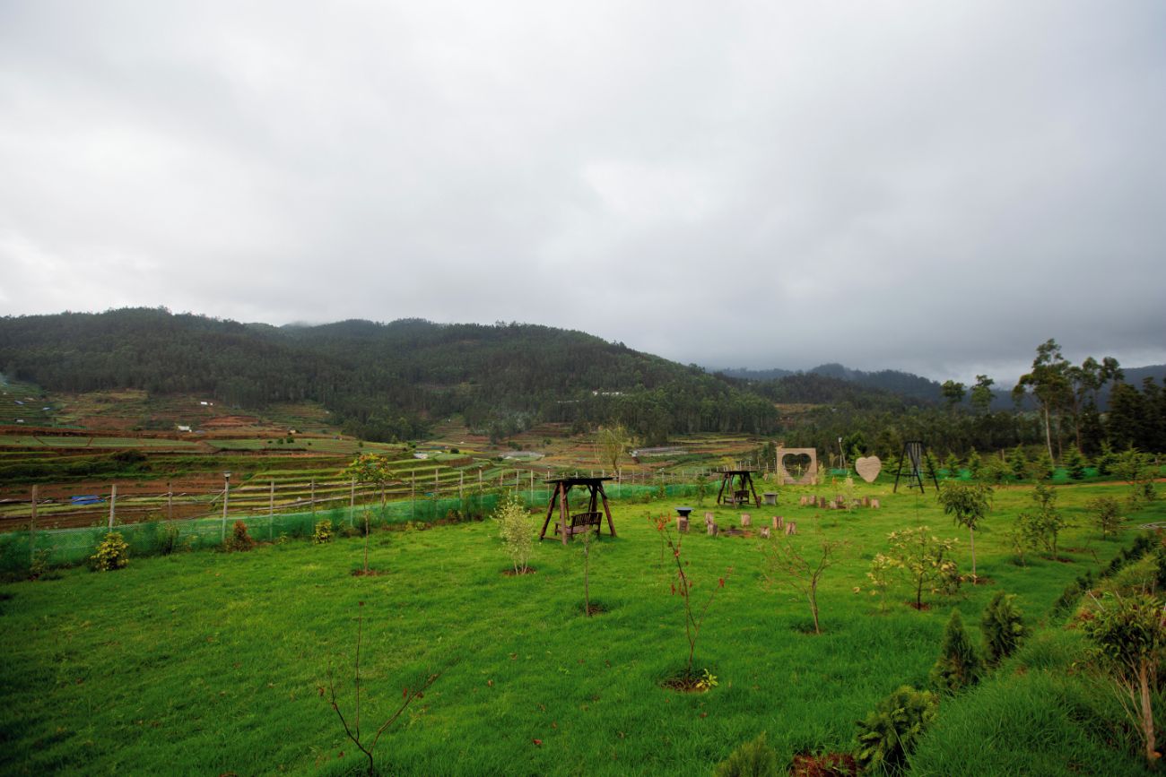 A rural landscape with rolling hills, a fenced field, and a few scattered trees.