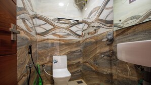 Un baño con pared de mármol, inodoro, un bidé verde y zona de ducha.