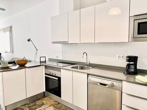 Eine moderne Küche mit weißen Schränken, Edelstahlgeräten, einer Kaffeemaschine und einer Schüssel auf der Arbeitsfläche.