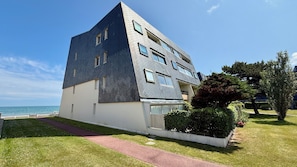 Ein modernes Gebäude mit einem markanten, dreieckigen Dach, einem gepflasterten Weg und Blick auf das Meer.