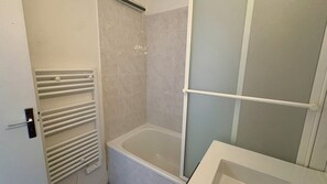 Ein Badezimmer mit einer Badewanne, einer Duschkabine und einem Handtuchhalter.