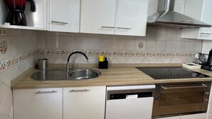 Una cucina con mobili bianchi, un lavello in acciaio inossidabile, una lavastoviglie e un forno.