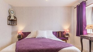 Een hotelkamer met een bed, twee nachtkastjes met lampen, een klok aan de muur en paarse gordijnen.