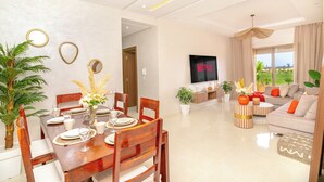 A modern living room with a dining area, a flat-screen TV, and a view of the outdoors. - Luxury apartment complex with a pool and gym, 10 minutes from Guéliz (marrakech)