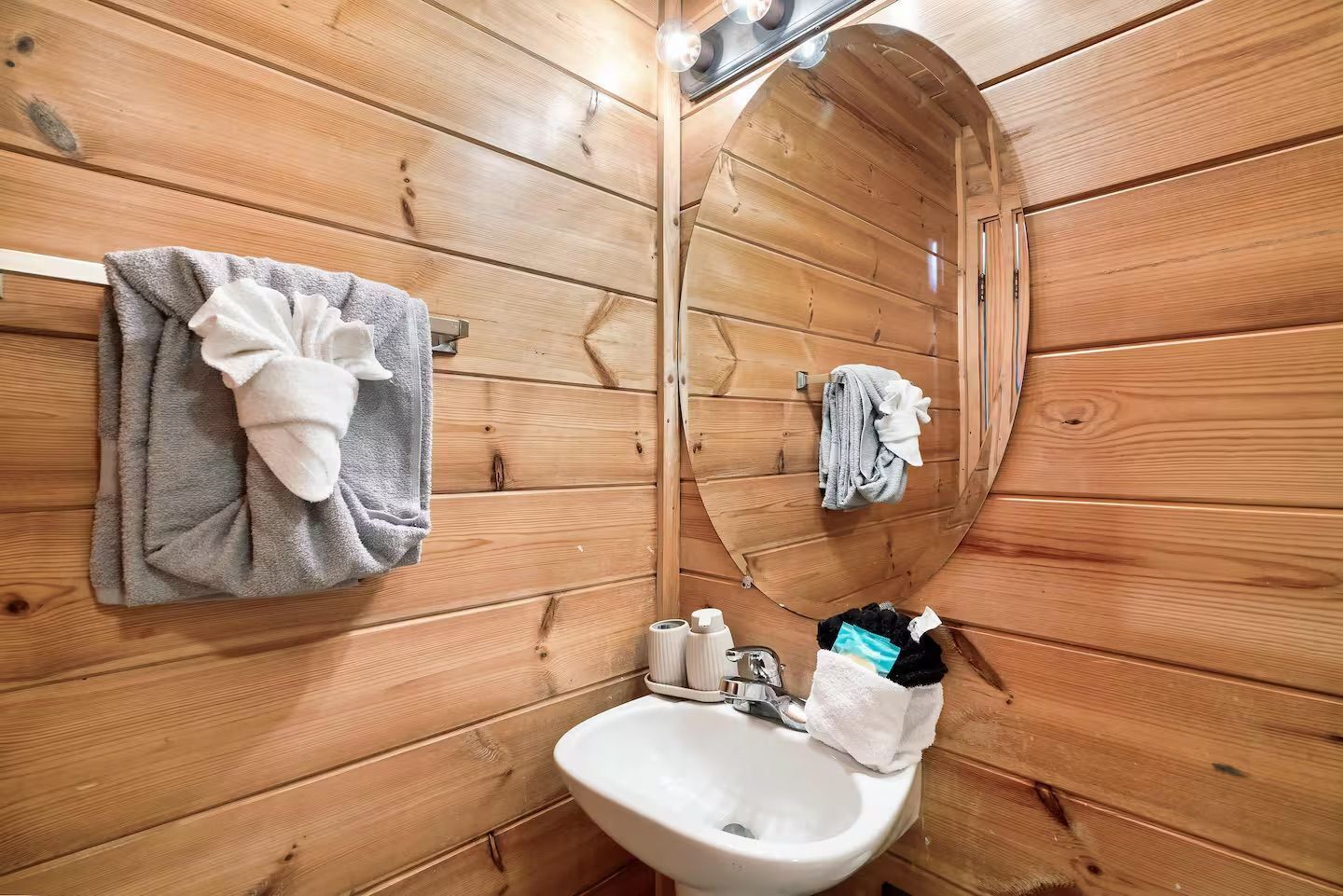 A wooden interior with a sink, towel rack, and a mirror.