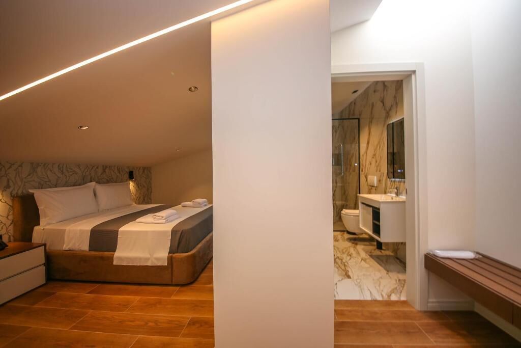 Un dormitorio moderno con cama, mesita de noche y velador.