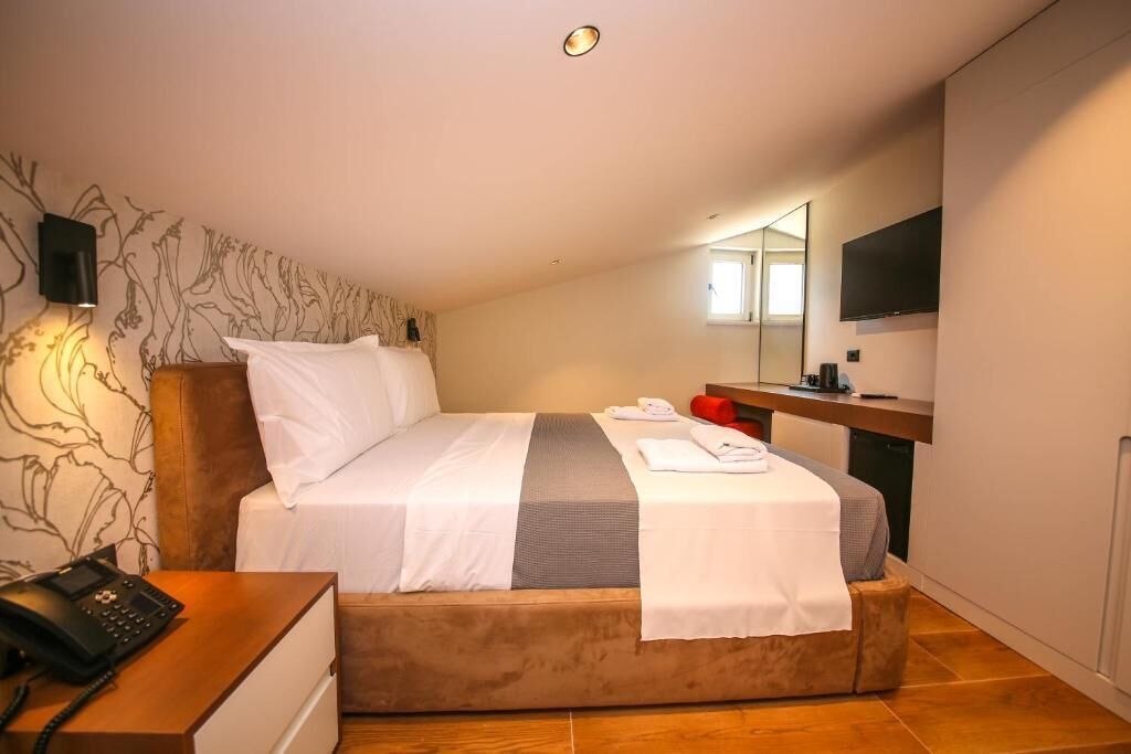 A hotel room with a bed, a desk with a telephone, a television, and a bathroom.