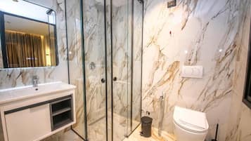 Un baño moderno con ducha de vidrio, lavamanos blanco y retrete.