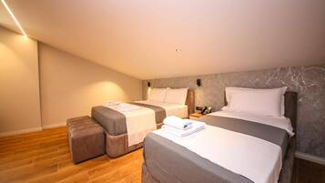 Quarto de hotel com duas camas, um pequeno espaço de estar e parede com padrão marmorizado.