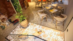 En restaurang med ett golv av glas, vita stenar och en växt i en trälåda.