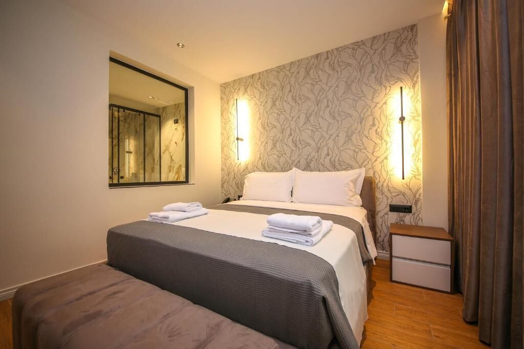 A hotel room with a large bed, a smaller bed, a nightstand, and a mirror.