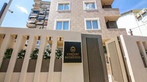 Entrada de un hotel con un cartel que dice 'COMFORT BOUTIQUE HOTEL' y un acceso con portón.