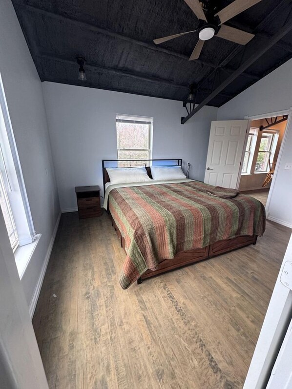 A bedroom with a bed, a ceiling fan, a window, and a door. - Incredible Spacious Rental with Fantastic Activities for an Unforgettable Family Adventure by the Lake in Cookson, Oklahoma (Cookson)