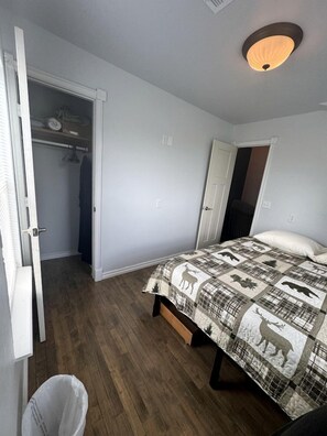 Quarto com cama, armário e porta que dá para outro cômodo.