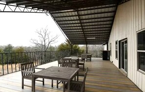 A covered outdoor patio with a table and chairs, a railing, and a view of the surrounding landscape. - Incredible Spacious Rental with Fantastic Activities for an Unforgettable Family Adventure by the Lake in Cookson, Oklahoma (Cookson)