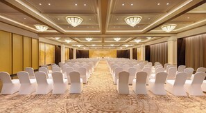 A conference room with rows of white chairs, a patterned carpet, and chandeliers on the ceiling. - Fortune Select Lucknow  (Lucknow)