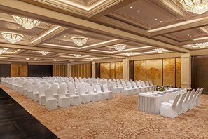 A conference room with rows of white chairs, a long table with a floral centerpiece, and ornate chandeliers. - Fortune Select Lucknow  (Lucknow)