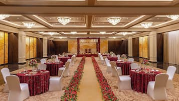 A banquet hall with tables set for a formal event, featuring a central aisle with floral decorations.