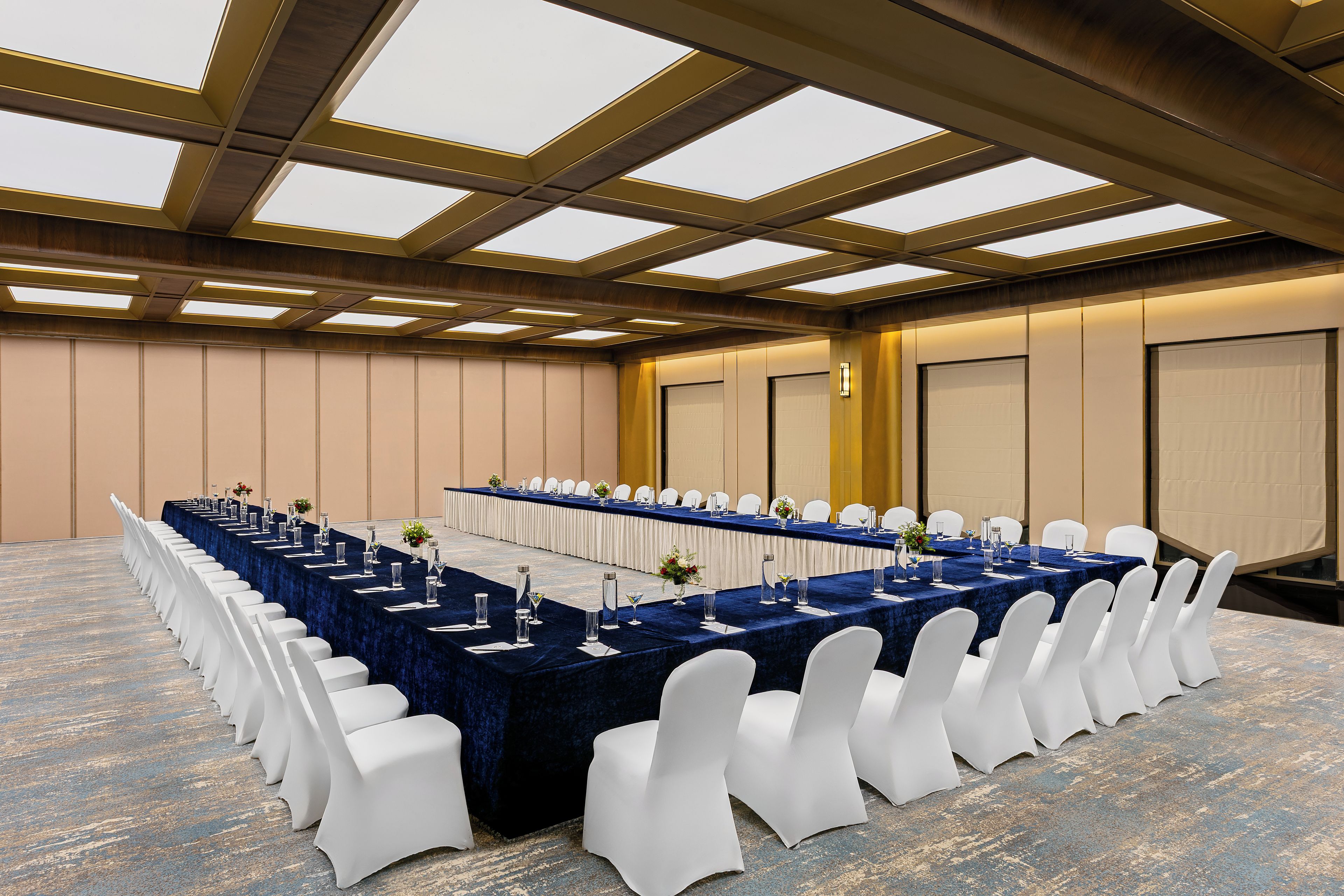A conference room with a long table, white chairs, and a high ceiling with skylights.