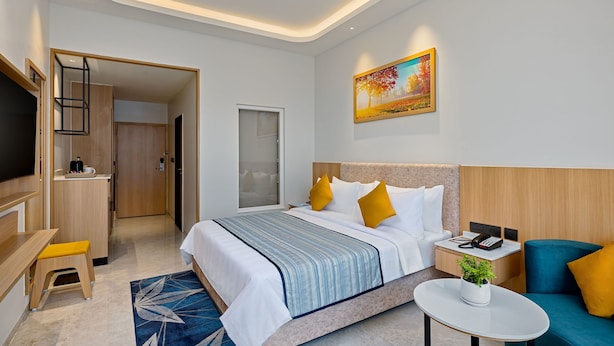 Een hotelkamer met een bed, nachtkastje, stoel, bureau en een televisie.