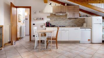A kitchen with a dining table, chairs, a refrigerator, and a stove.