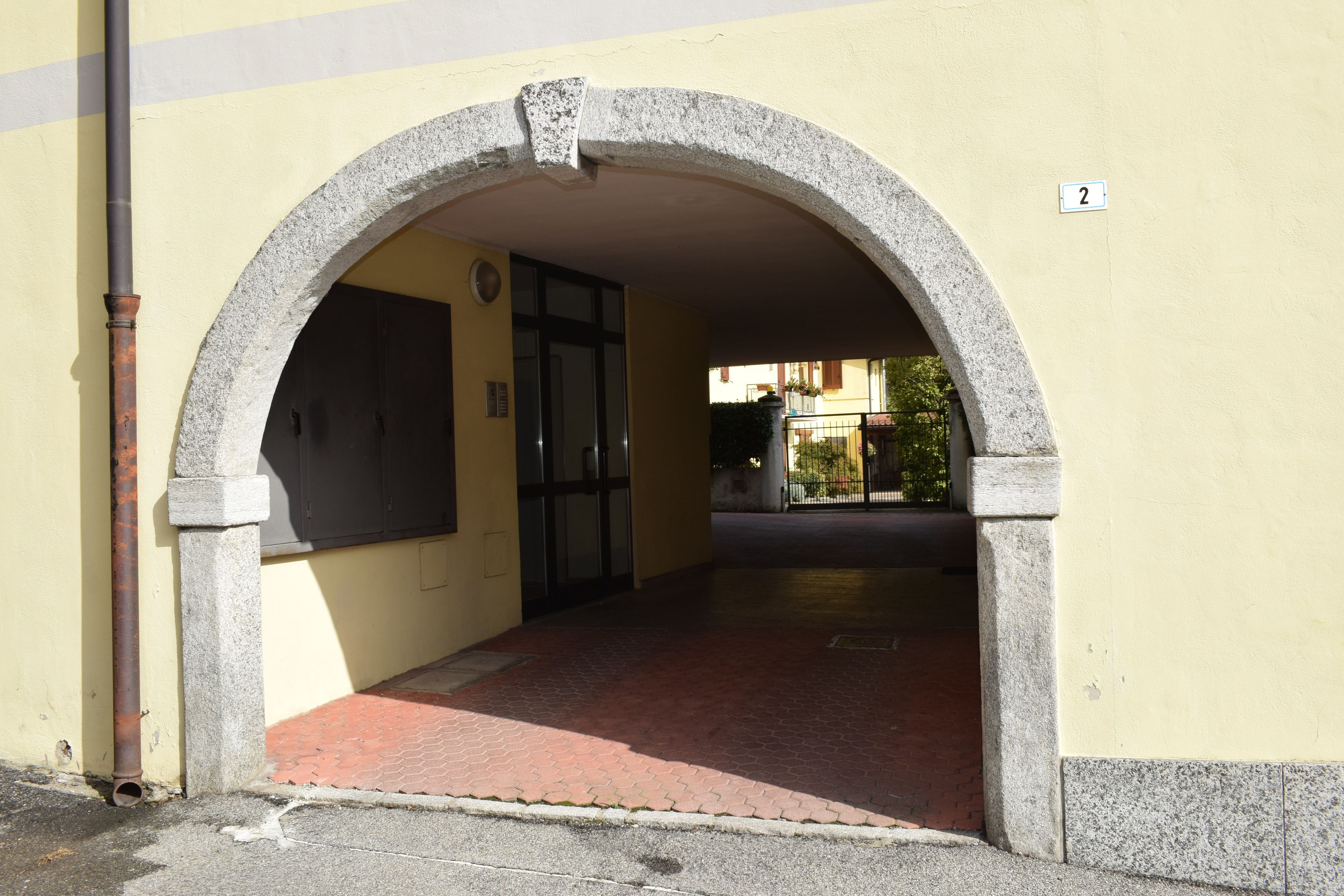 Ein bogenförmiger Eingang zu einem Gebäude mit Fliesenboden und einer Hinweisschild.