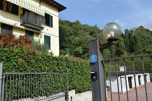 A gated entrance with a metal fence, a street lamp, and a building with a balcony.