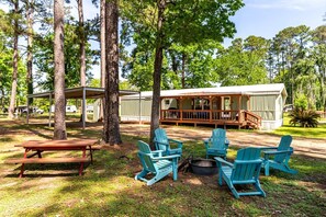 Un rustico chalet con un portico, un tavolo da picnic e diverse poltrone Adirondack.